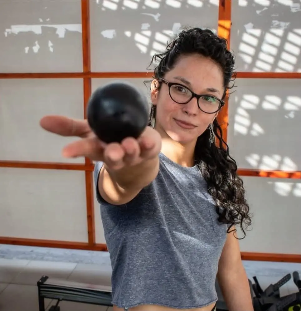 Niria sonríe y extiende una pelota pequeña hacia la cámara